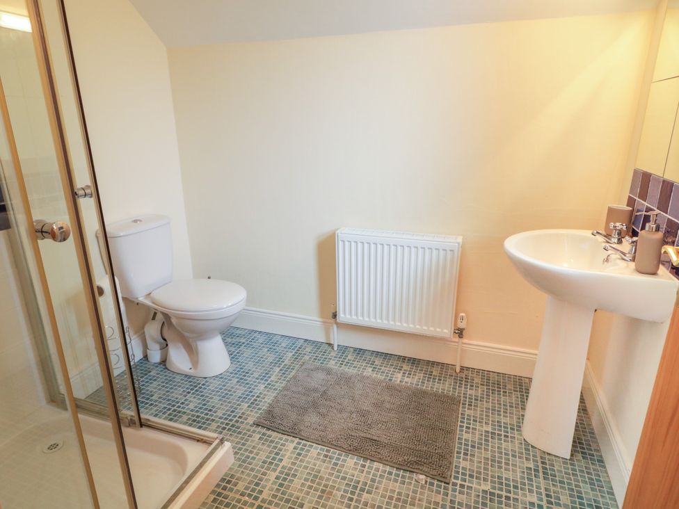 A bathroom with a shower, toilet, sink and radiator at Shane's Cottage, Falcarragh, County Donegal