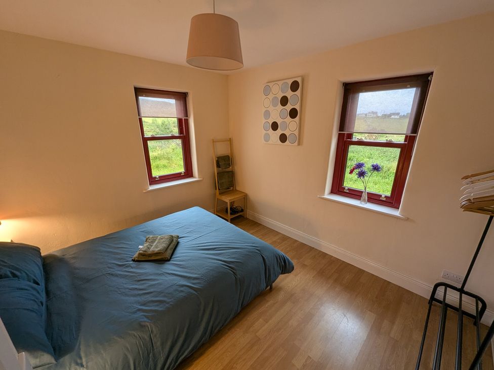 A bedroom with a bed and shelves at Shane's Cottage, Falcarragh, County Donegal