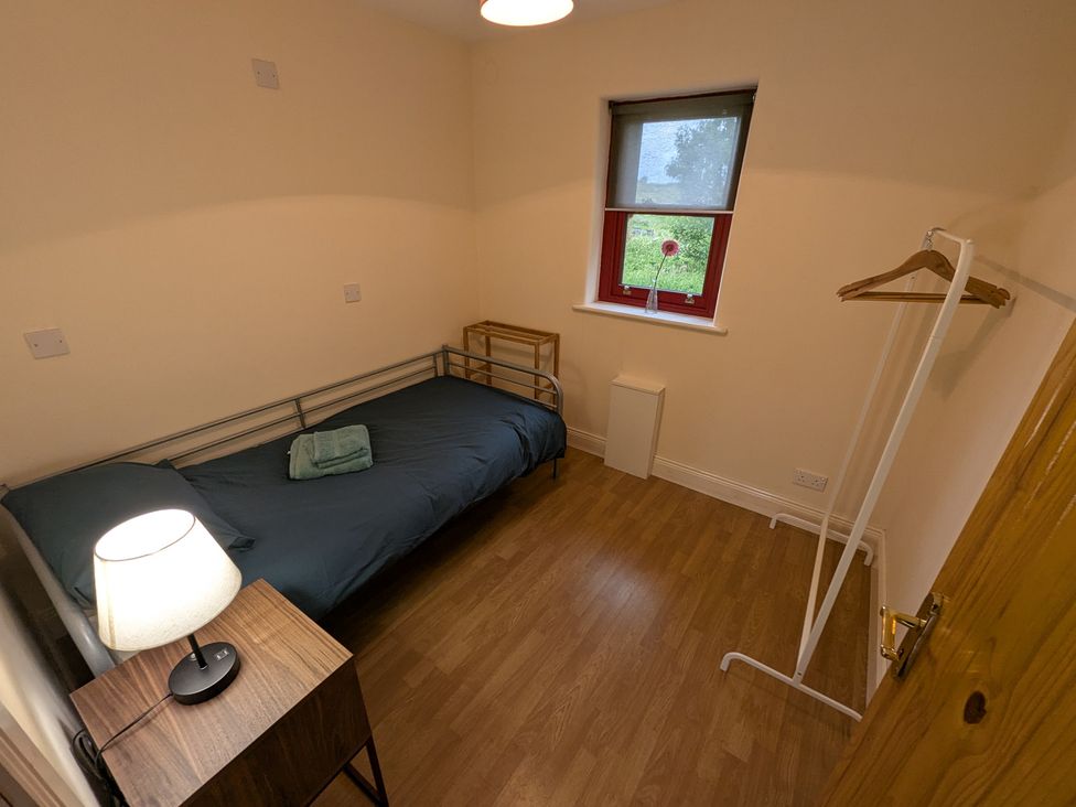 A bedroom with a bed and lamp at Shane's Cottage in Falcarragh, County Donegal