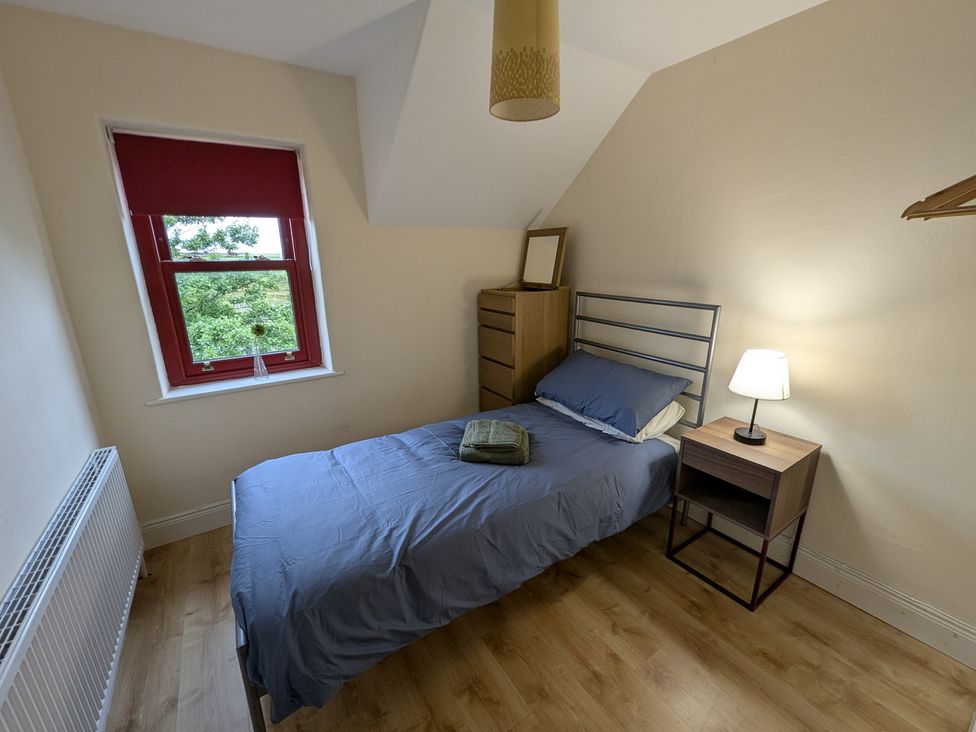 A bedroom with a single bed and desk lamp at Shane's Cottage in Falcarragh, County Donegal