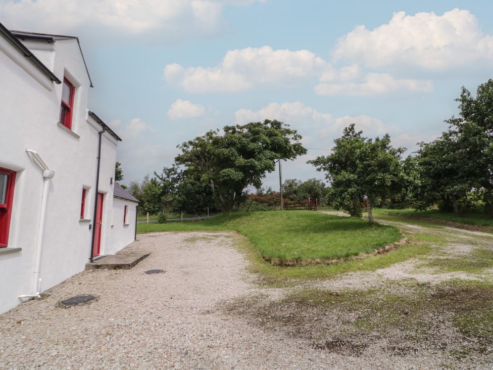 An outdoor view of a house with a gravel driveway and surrounding trees at Shane's Cottage in Falcarragh, County Donegal