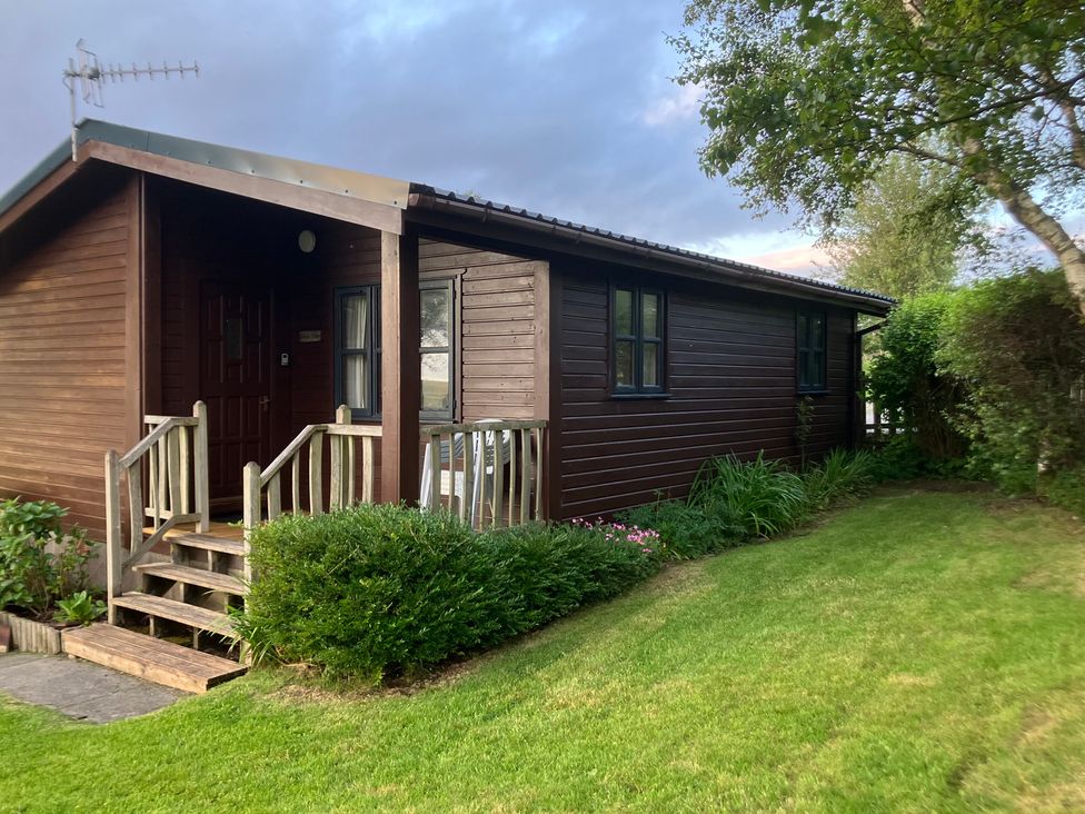 A wooden cabin with steps and lawn at Island View Lodge Back of Keppoch near Arisaig