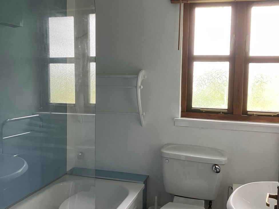 A bathroom with a bathtub, toilet, sink, and window at Island View Lodge Back of Keppoch near Arisaig