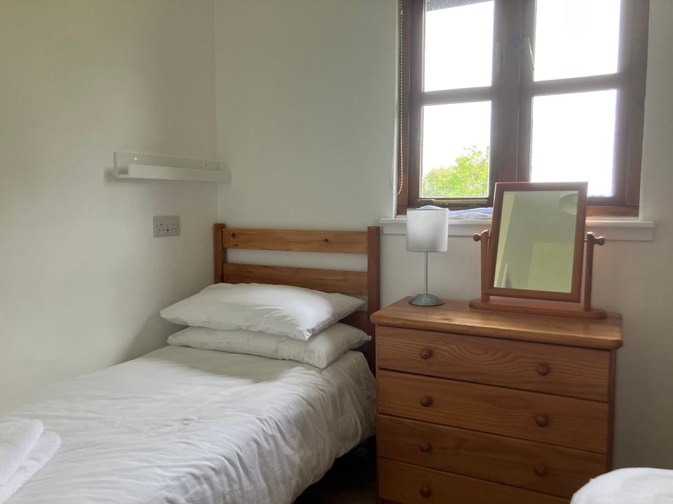 A bedroom with a single bed and wooden furniture at Island View Lodge Back of Keppoch near Arisaig