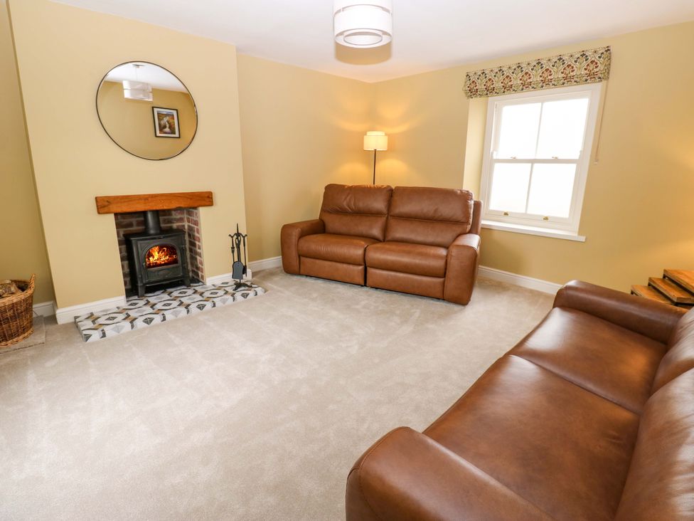A living room with brown sofas and a fireplace at Peace Cottage in Langton near Gainford
