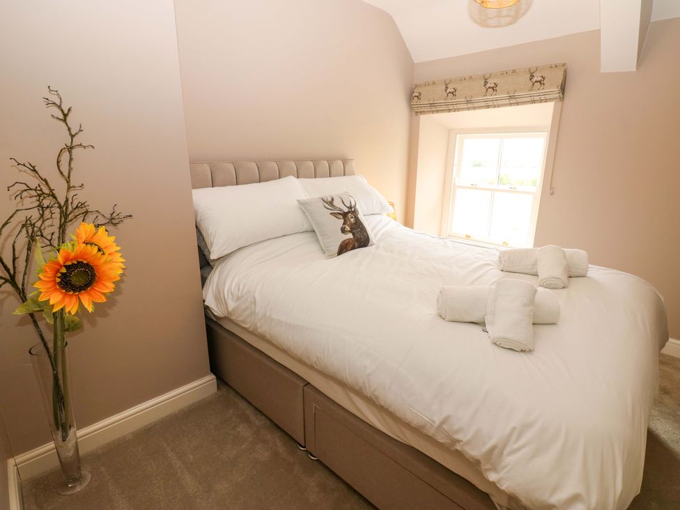 A bedroom with a bed and flower vase at Peace Cottage in Langton near Gainford