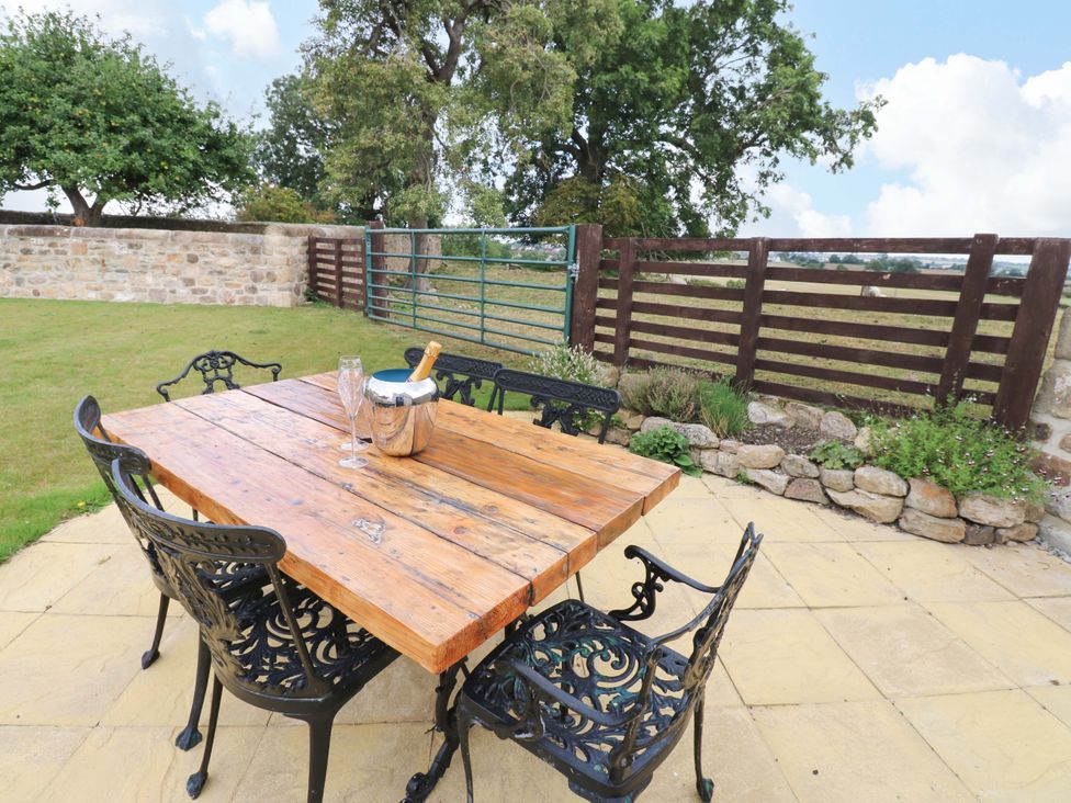 An outdoor seating area with a wooden table and chairs at Peace Cottage Langton near Gainford
