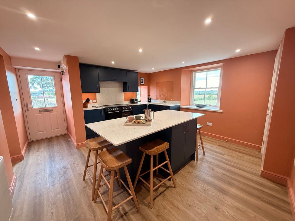 A kitchen with a counter and stools at Peace Cottage in Langton near Gainford