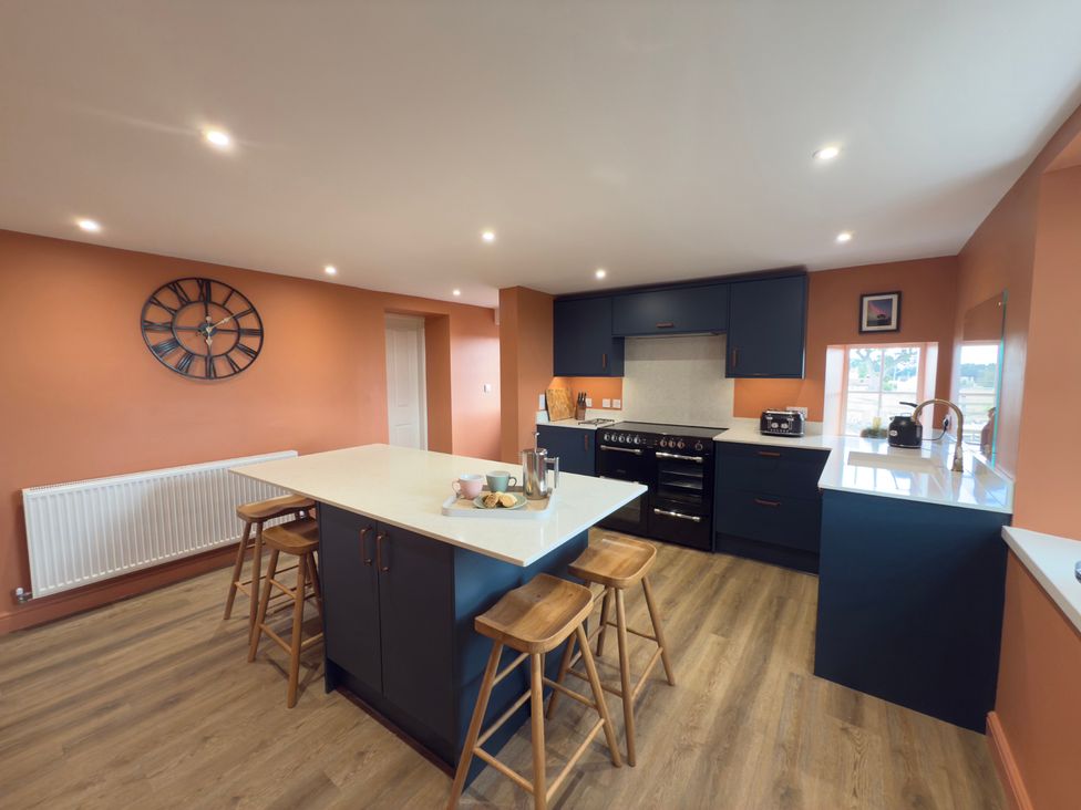 A kitchen with an island, stools, and appliances at Peace Cottage in Langton near Gainford