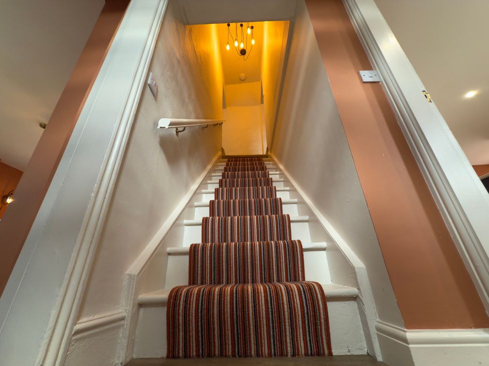 A staircase with a carpet runner and a light fixture at Peace Cottage in Langton near Gainford