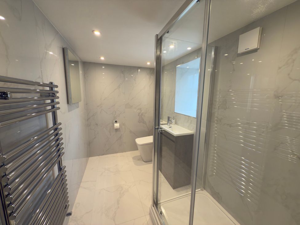 A bathroom with a shower, toilet, sink, and towel radiator at Peace Cottage Langton near Gainford