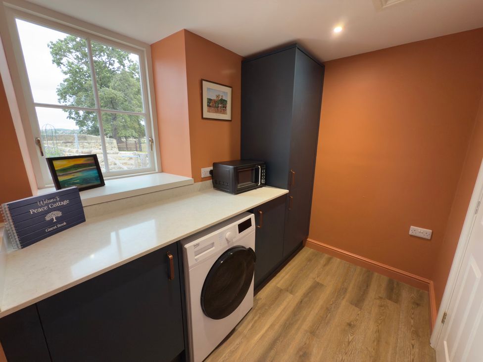A utility room with a washing machine and microwave at Peace Cottage in Langton near Gainford