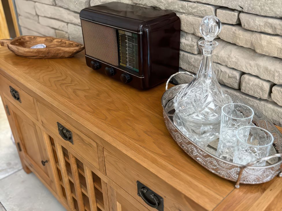 A living room with a radio, decanter and glasses on a wooden furniture at 12 Queen Street in Keighley