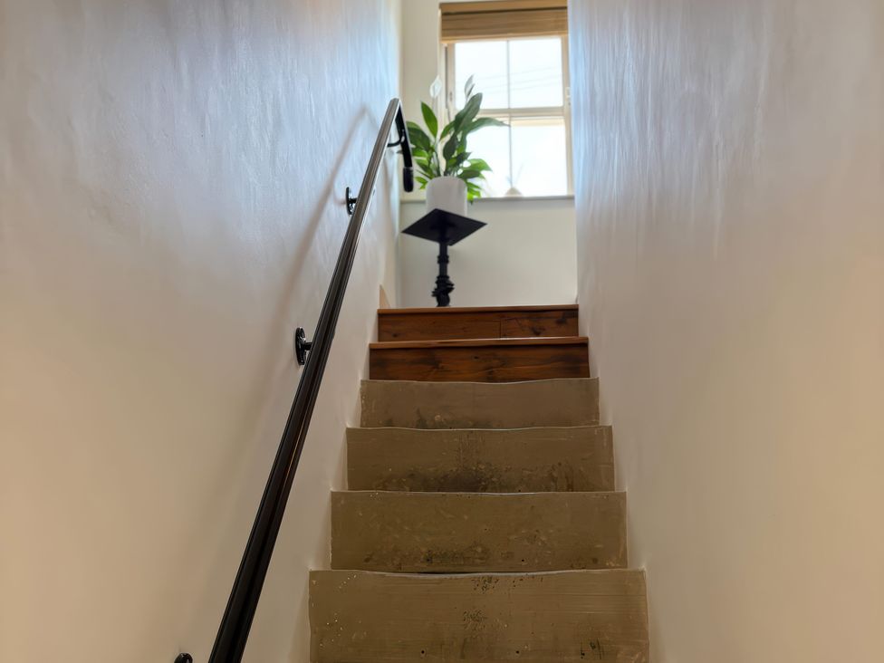 A staircase leading up with a plant and table at 12 Queen Street in Keighley