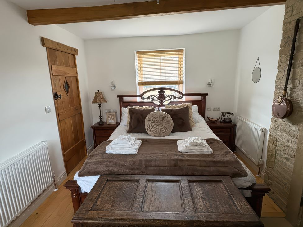 A bedroom with a bed, nightstand, lamp, and window at 12 Queen Street in Keighley