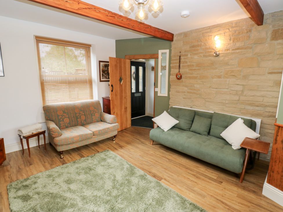 A living room with a sofa and table at Hivewood Cottage in Haworth