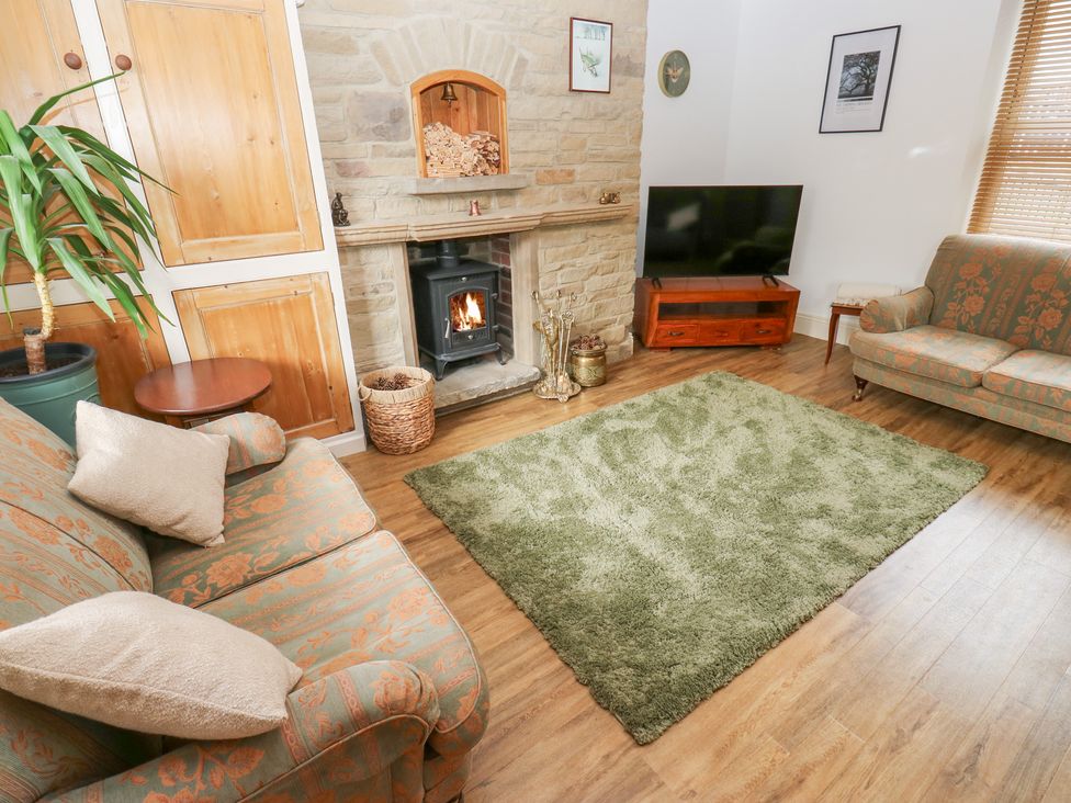 A living room with a fireplace and television at Hivewood Cottage in Haworth