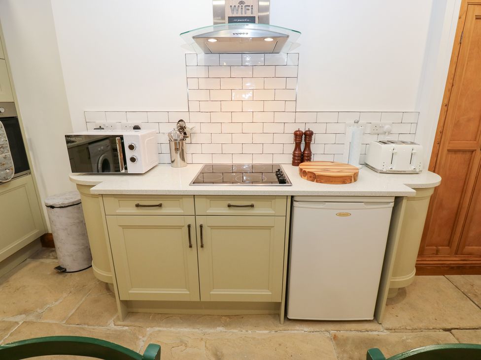 A kitchen with stove, microwave, and fridge at Hivewood Cottage in Haworth