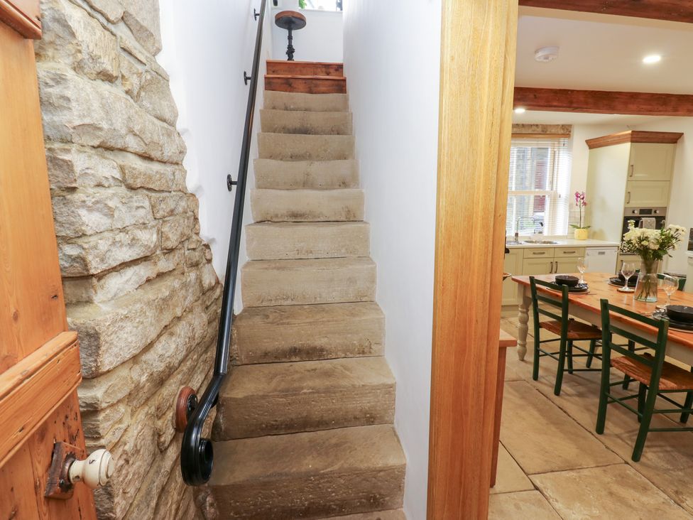 Stairs leading to the upper level with a view of the kitchen at Hivewood Cottage in Haworth