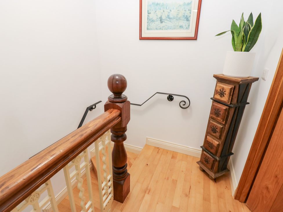 A staircase with wooden railing and decorative items at Hivewood Cottage in Haworth