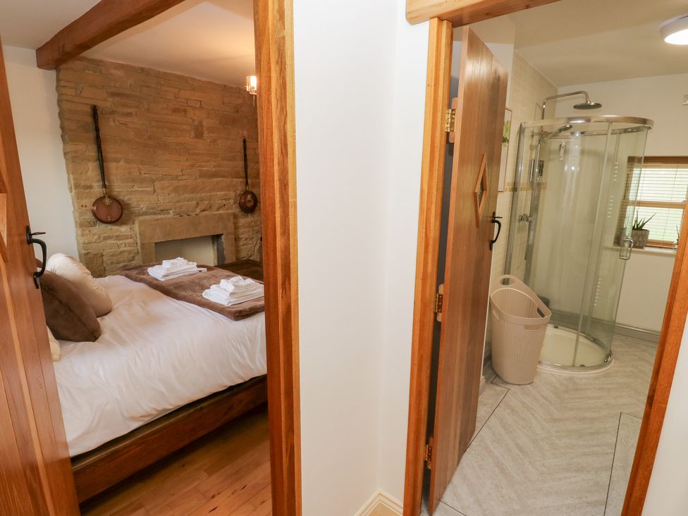 A bedroom with a bathroom featuring a shower at Hivewood Cottage in Haworth