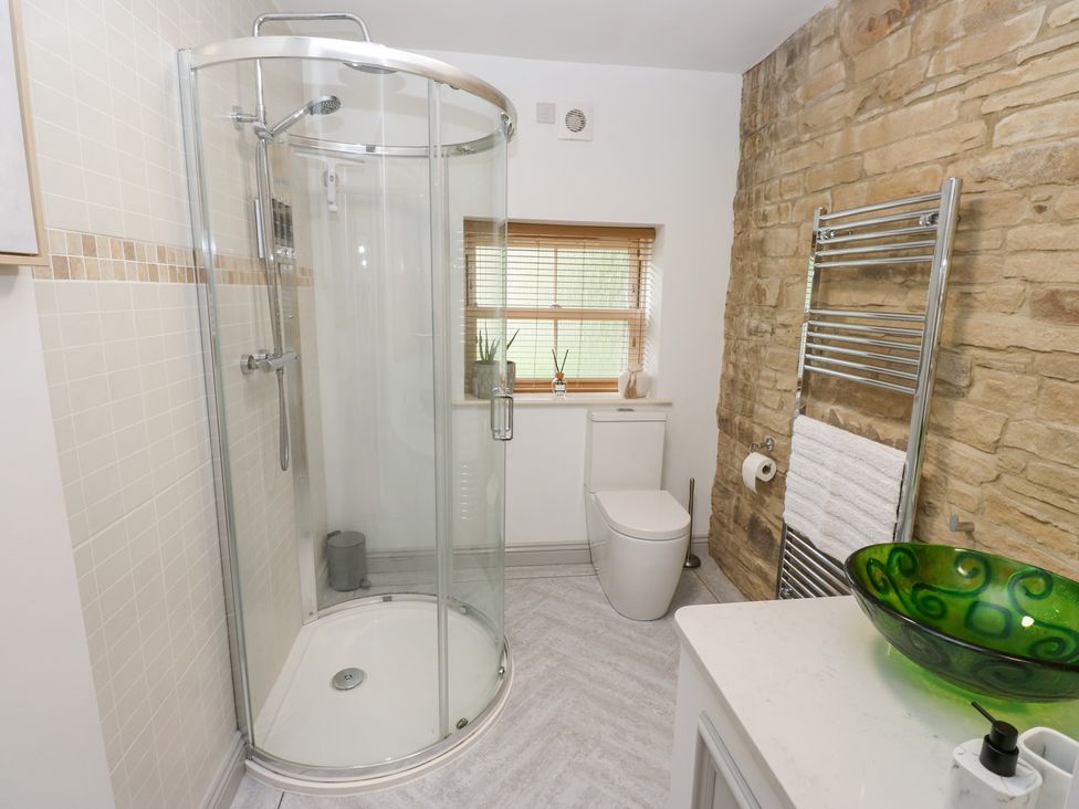 A bathroom featuring a shower and toilet at Hivewood Cottage in Haworth