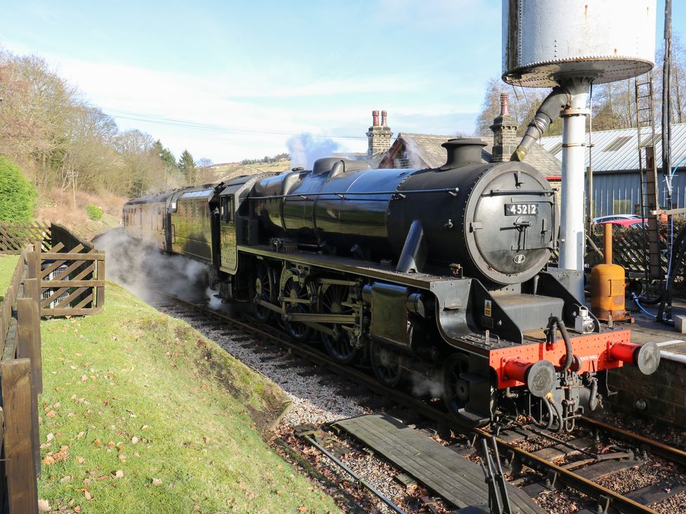 A steam locomotive at a railway station at Hivewood Cottage in Haworth