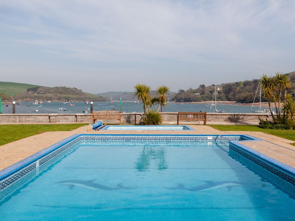 An outdoor area with a swimming pool and a view of water and boats at 43 The Salcombe Salcombe
