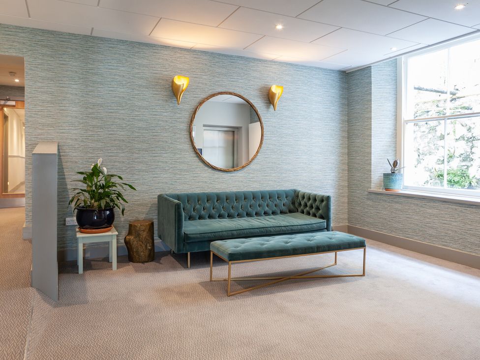 A lounge with a sofa, bench, mirror and plant at 43 The Salcombe, Salcombe