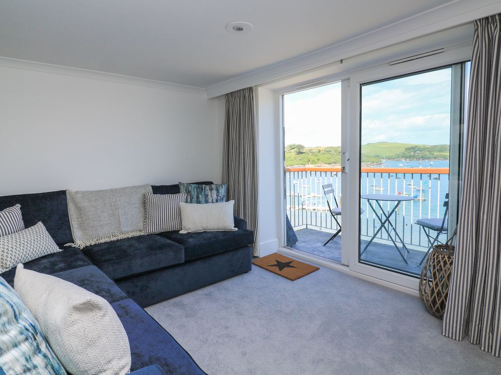 A living room with a sofa and sliding door leading to a balcony at 43 The Salcombe in Salcombe