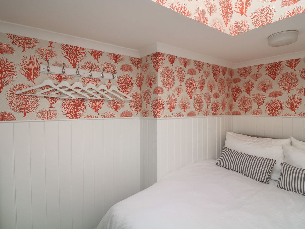 A bedroom with a bed and coat rack at 43 The Salcombe in Salcombe