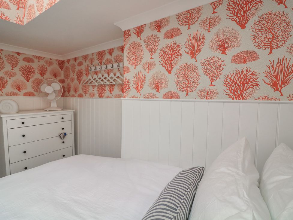 A bedroom with a bed, chest of drawers, and a fan at 43 The Salcombe, Salcombe