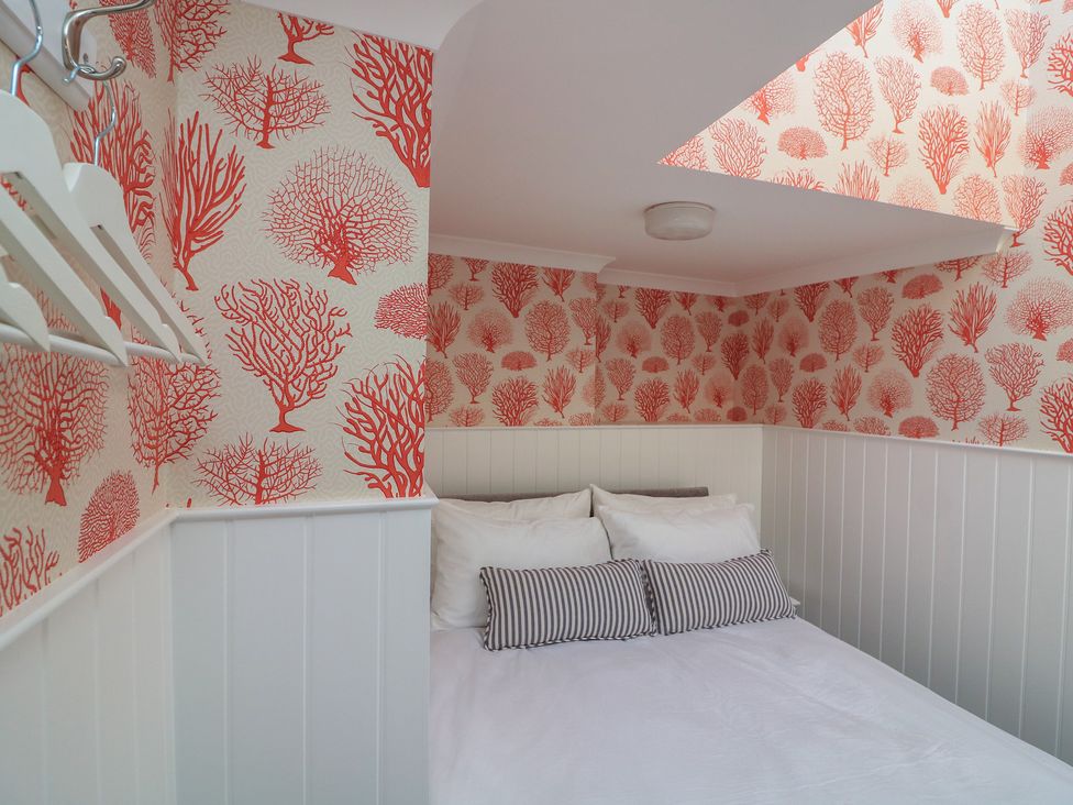 A bedroom with a bed and coathangers at 43 The Salcombe in Salcombe