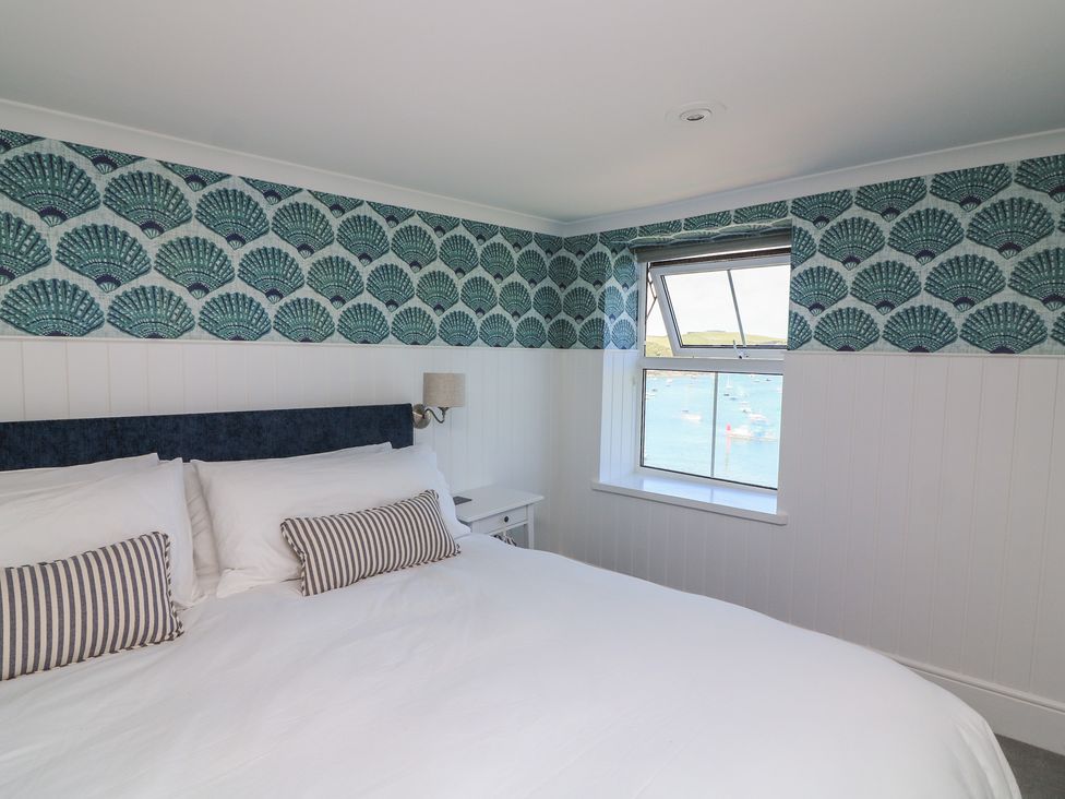 A bedroom with a bed and a window overlooking the water at 43 The Salcombe in Salcombe