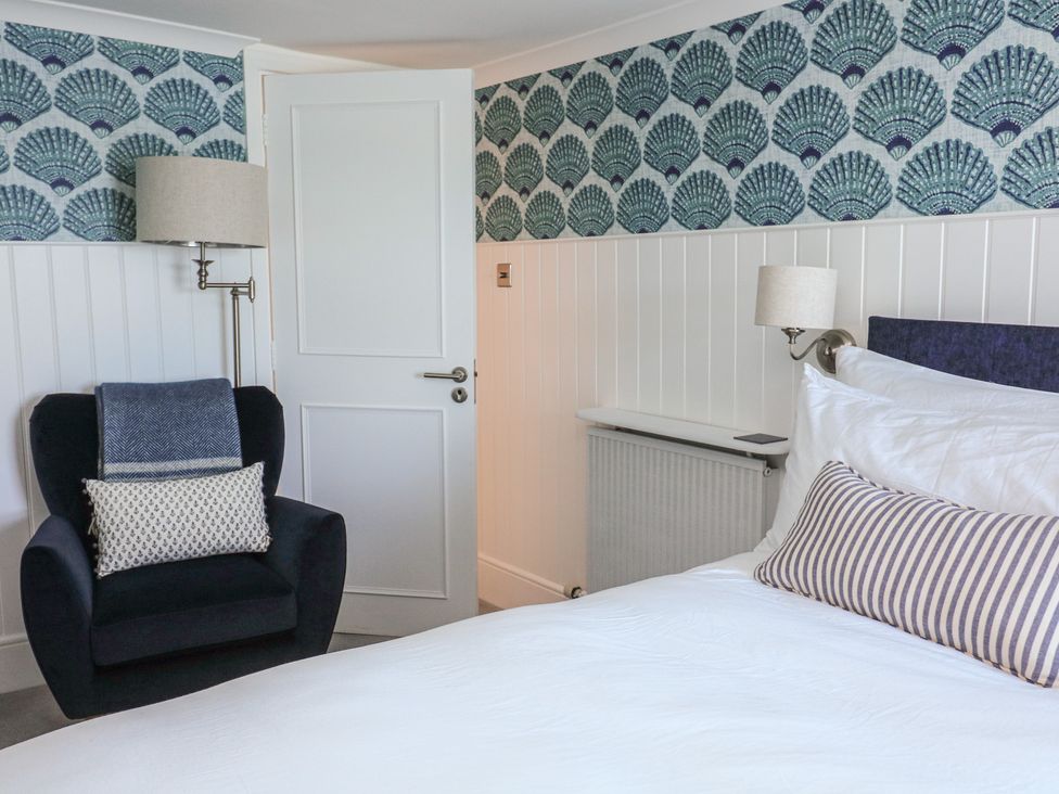 A bedroom with a bed and chair at 43 The Salcombe in Salcombe