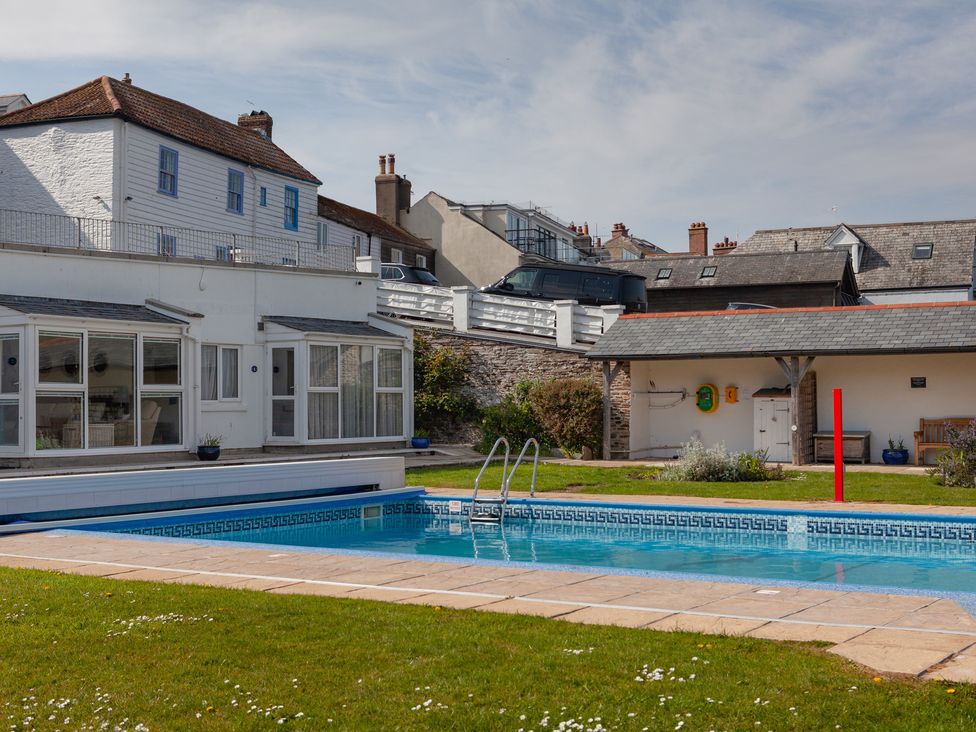 An outdoor area with a swimming pool and a glass conservatory at 43 The Salcombe in Salcombe