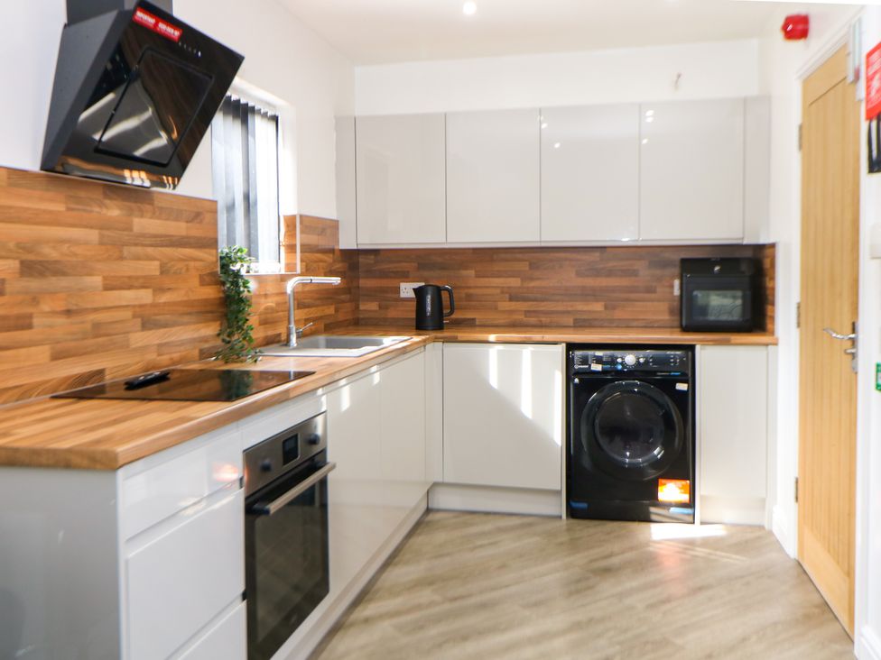 A kitchen featuring a stove, oven, sink, and washing machine at Don Valley Apartment A