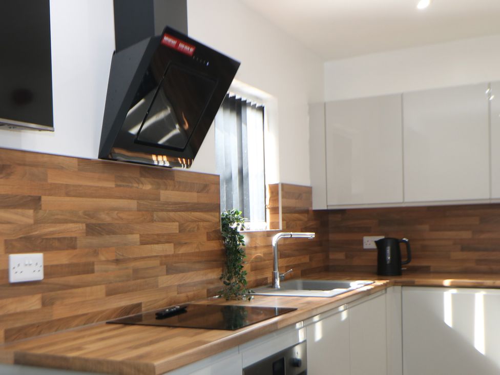 A kitchen with sink, cooker, kettle and extractor hood at Don Valley Apartment A