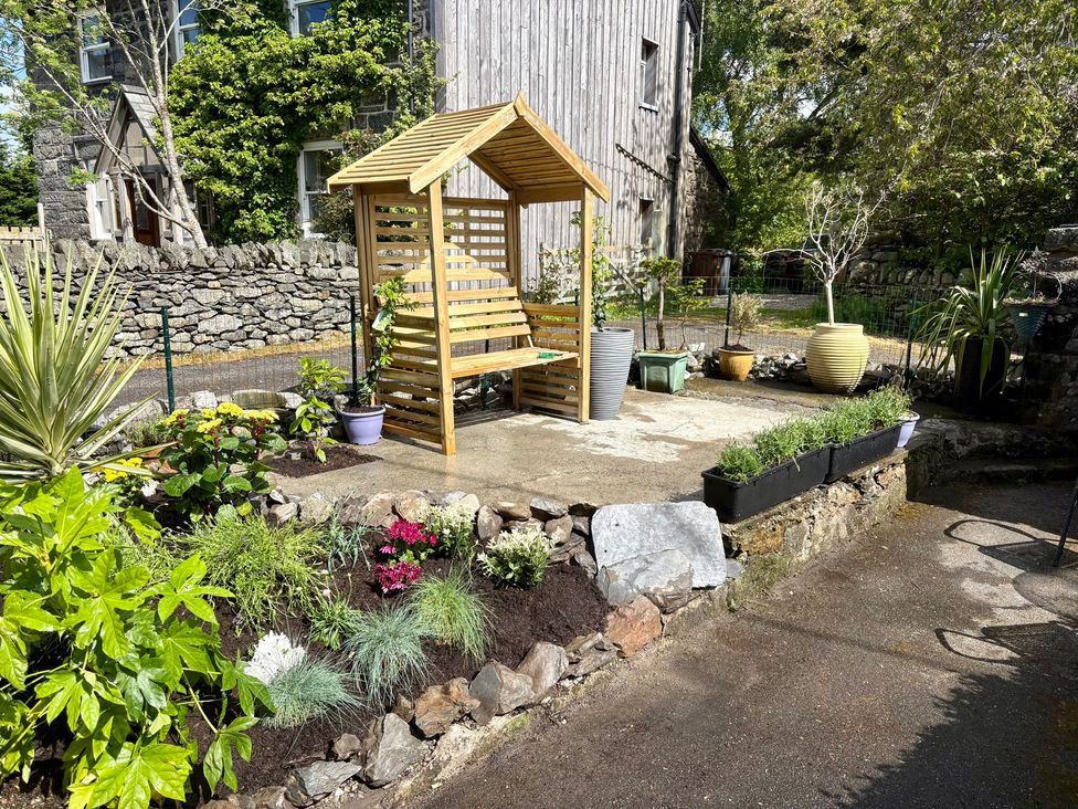 A garden with a bench and flower beds at Gwynfa in Ysbyty Ifan