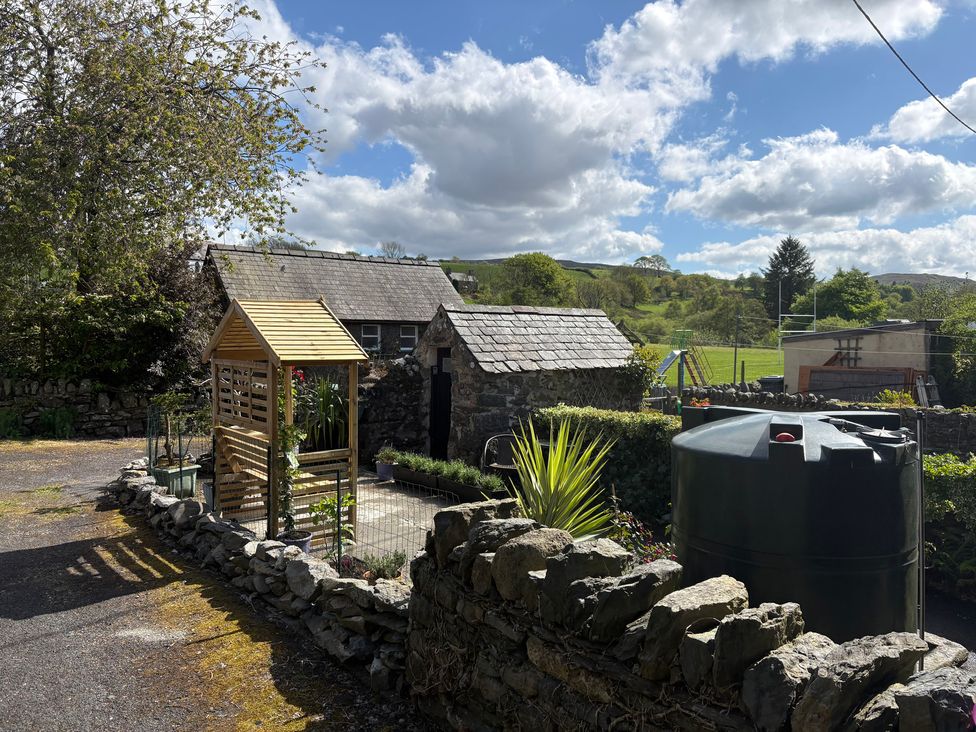 A garden with a wooden shed and water tank at Gwynfa in Ysbyty Ifan