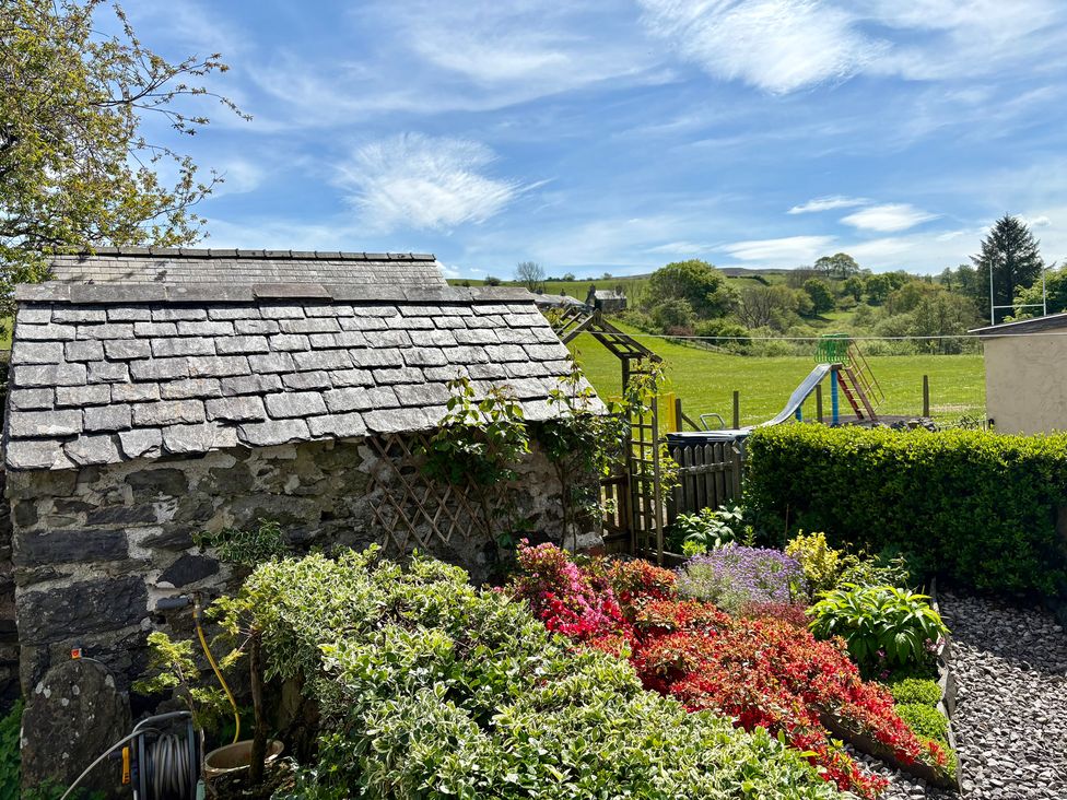 A garden with flowers and a shed at Gwynfa in Ysbyty Ifan