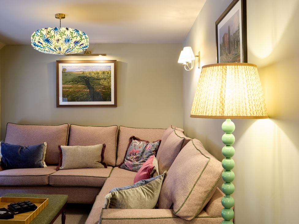 A living room with a pink sofa and decorative cushions at The Dovecote in Matlock