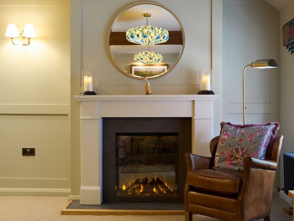 A living room with a fireplace and a chair at The Dovecote in Matlock