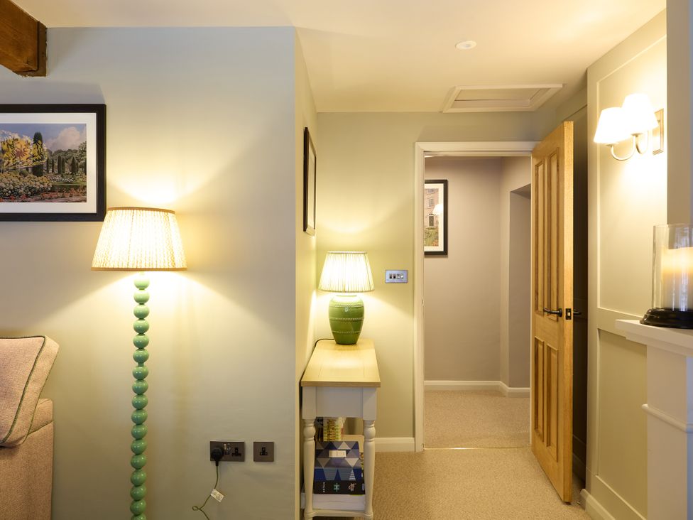 A hallway with a lamp, table, and door at The Dovecote in Matlock