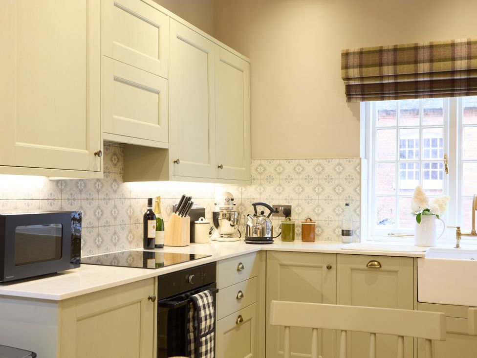 A kitchen with cabinets, microwave, kettle, and sink at The Dovecote in Matlock