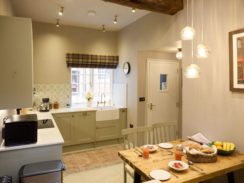 A kitchen with a dining area and a basket of fruit at The Dovecote in Matlock