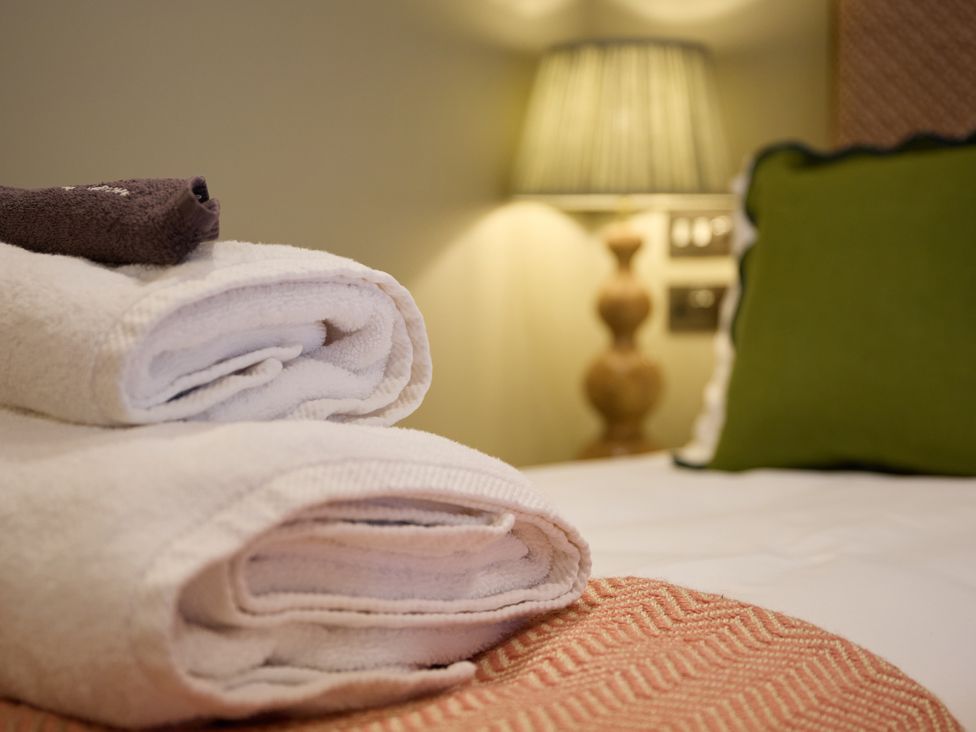 Towels and a cushion on a bed at The Dovecote in Matlock