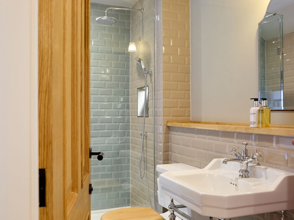 A bathroom with a shower, sink and mirror at The Dovecote in Matlock
