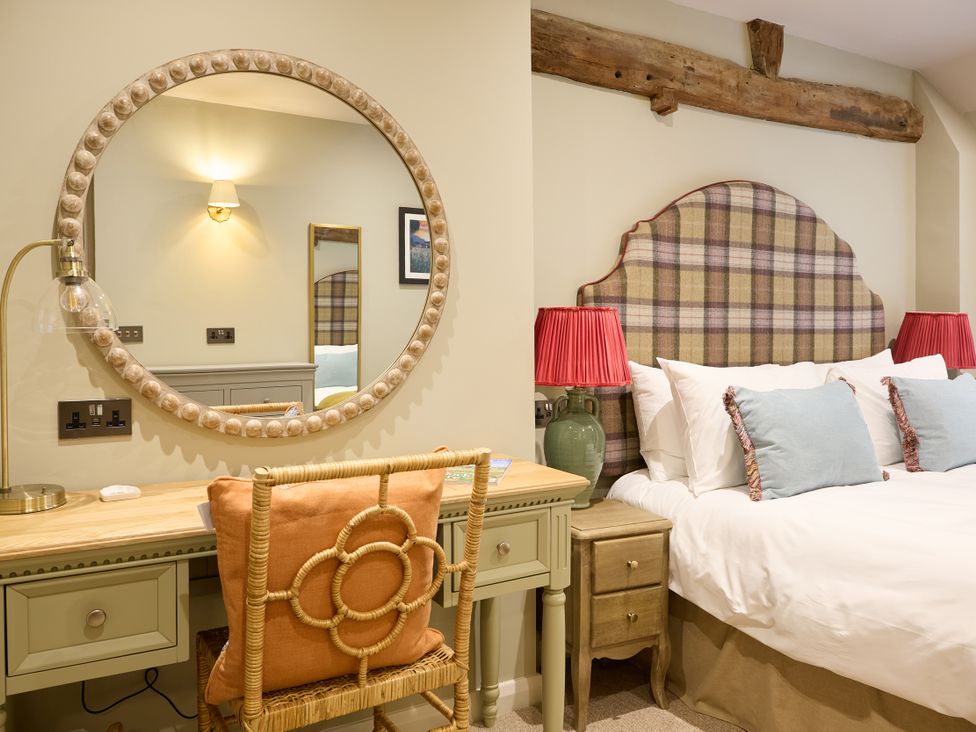 A bedroom with a bed, desk, lamp, and mirror at The Dovecote in Matlock