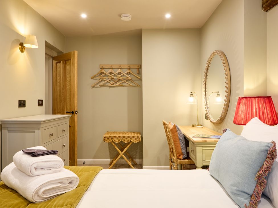 A bedroom with a bed, desk, and mirror at The Dovecote in Matlock